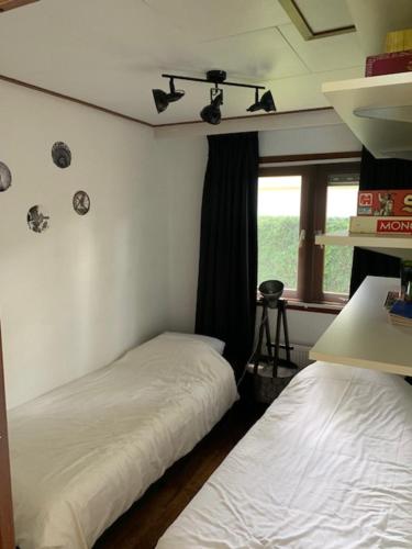 una stanza con due letti e una finestra di Dubbele chalet op recreatiepark Topparken op de Veluwe in Beekbergen met grote vrije tuin en eigen parkeerplaats a Beekbergen
