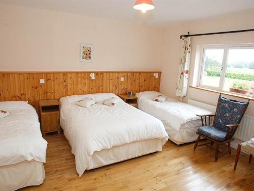 巴納赫的住宿－敦克羅美茵住宿加早餐旅館，一间卧室设有两张床、一把椅子和一个窗户。