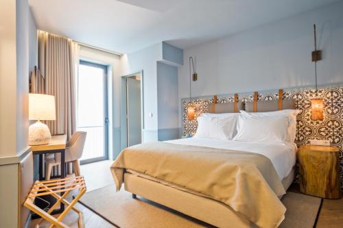a bedroom with a large bed and a desk with a lamp at Pur Oporto Boutique Hotel by actahotels in Porto