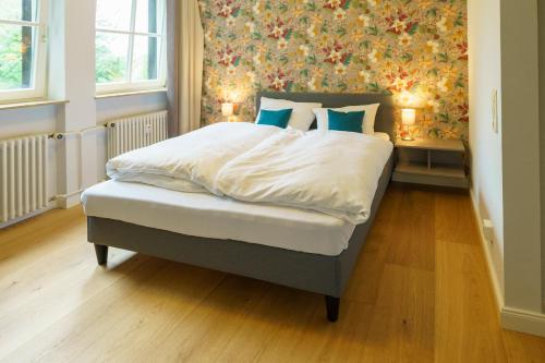 a bedroom with a bed with white sheets and blue pillows at Gästehaus Sonnenhof in Kassel