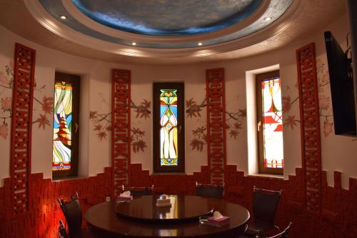 a dining room with a table and stained glass windows at Ureni Hotel in Kʼasakh