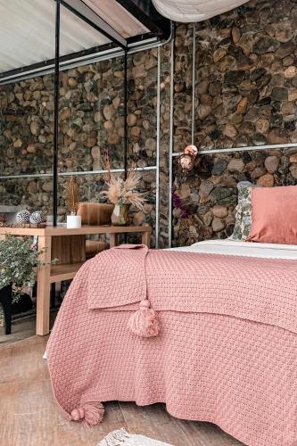 a bedroom with a bed with a pink blanket at Intrepido Glamping in Chinchiná