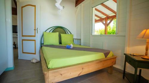 a bedroom with a bed with green pillows and a window at Maison avec vue sur mer à Saint-François, confortable et équipée in Saint-François