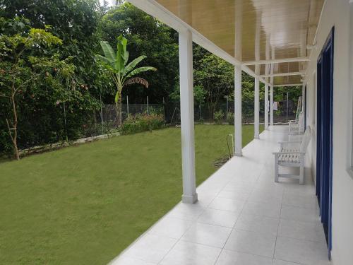 a porch of a house with a green lawn at Puerta Azúl Capurganá in Capurganá