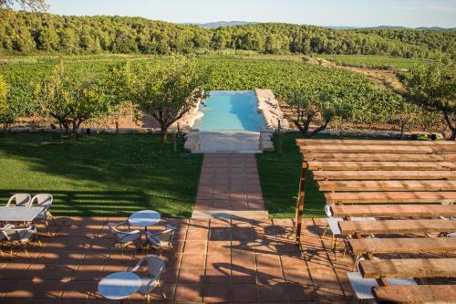 Font-Rubí的住宿－Casa Gran 1771 - MontRubí Winery Hotel - Adults Only，游泳池前带桌椅的天井