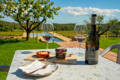 een tafel met een fles wijn en twee glazen bij Casa Gran 1771 - MontRubí Winery Hotel - Adults Only in Font-Rubí