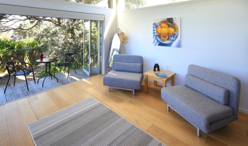 a living room with two chairs and a table at Tutiri in Oneroa in Oneroa