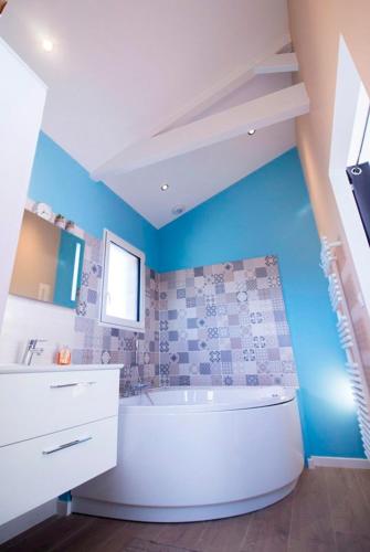 La salle de bains est pourvue d'une baignoire blanche et d'un mur bleu. dans l'établissement Chambres d'hotes du Mas de la Corniche, à Joyeuse