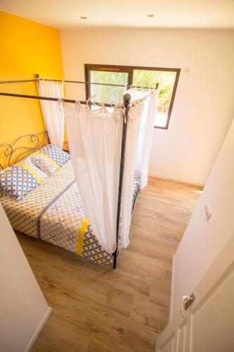 - une chambre avec un lit avec des rideaux et une fenêtre dans l'établissement Chambres d'hotes du Mas de la Corniche, à Joyeuse
