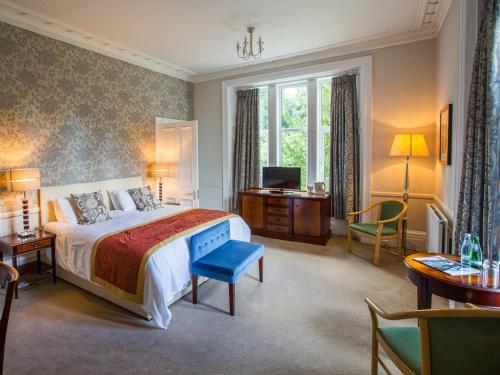 um quarto com uma cama, uma secretária e uma televisão em Balcary House Hotel em Hawick
