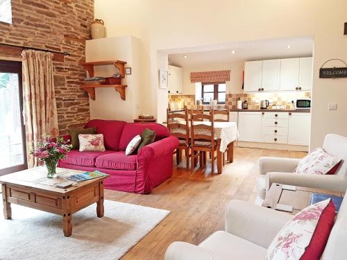 a living room with a red couch and a table at River Cottage@Cwm Mill - Riverside Family Holidays in the Black Mountains in Hereford