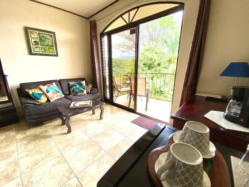 a living room with a couch and a large window at Hotel Vista Linda Montaña in Alajuela City