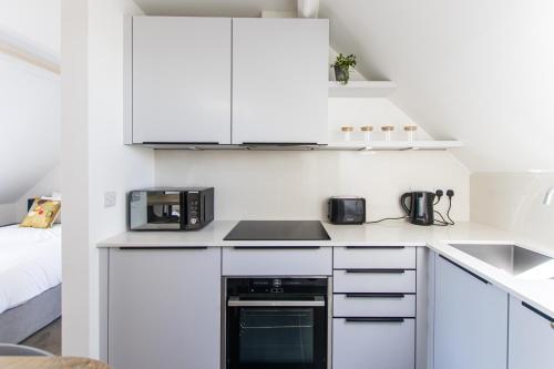 a kitchen with white cabinets and a stove top oven at Bright & Beautiful Studio Flat in Bristol! in Bristol