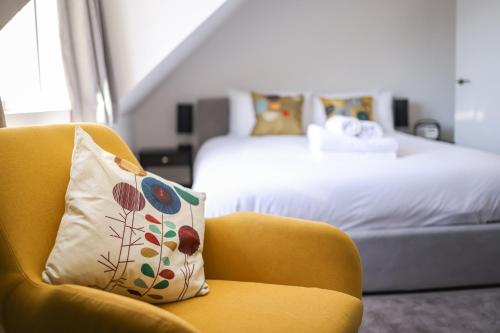 a yellow chair with a pillow in a hotel room at Bright & Beautiful Studio Flat in Bristol! in Bristol
