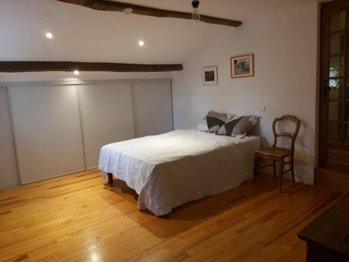 a bedroom with a white bed and a wooden floor at Gite du jardin du Bout du Ciel in Céron