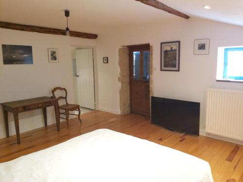 a bedroom with a bed and a table and a desk at Gite du jardin du Bout du Ciel in Céron
