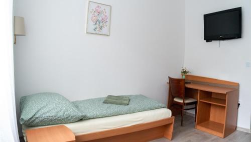 a small bedroom with a desk and a bed and a television at Ubytovanie SASINKOVA in Žilina