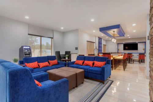 a living room with blue couches and a dining room at Comfort Inn & Suites Memphis East in Memphis