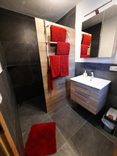 W łazience znajduje się biała umywalka i czerwone ręczniki. w obiekcie Ferienwohnung Silbernagel w mieście Kössen