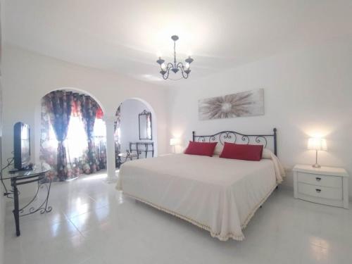 a white bedroom with a large bed and a chandelier at Tango House in Arona