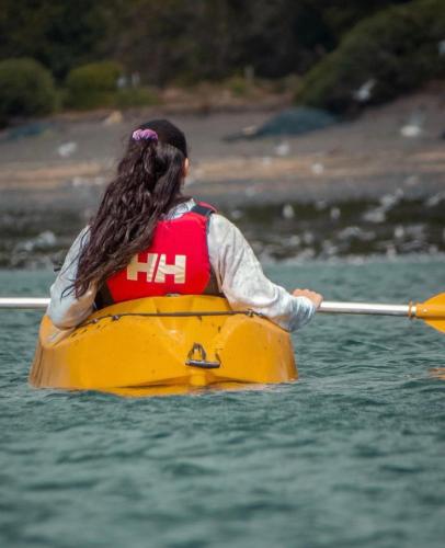 a woman in a yellow kayak in the water at El Reflejo Lodge Spa - Queilen - Chiloé in Queilén