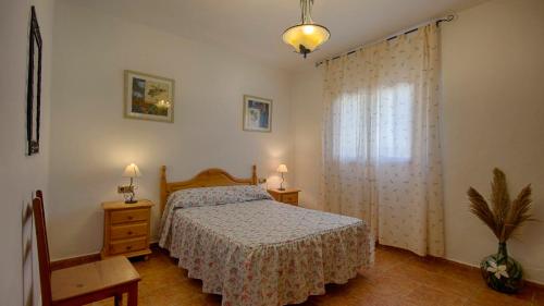 a bedroom with a bed and a chair and a window at Casa Tejo Sedella by Ruralidays in Sedella