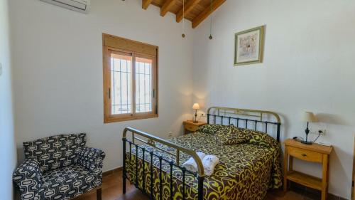 una camera con un letto e una sedia e una finestra di Casa Ramirez Almachar by Ruralidays ad Almáchar
