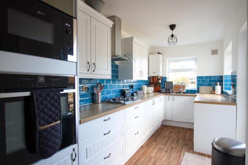 a kitchen with white cabinets and blue tiles at Contemporary Home in Friendly Easton, Free Parking in Bristol