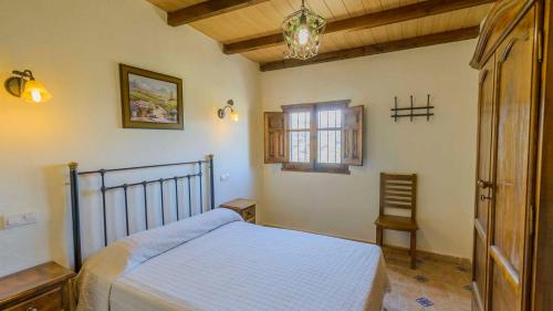 una camera con letto, finestra e sedia di Villa el Establo Montefrio by Ruralidays a Montefrío
