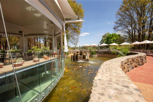 a restaurant with a pond in front of a building at Hotel & Glamping Huasca Sierra Verde in Huasca de Ocampo