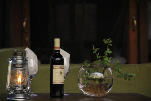 a bottle of wine next to a candle and a glass at Hoedspruit Raptors Lodge N16 in Hoedspruit