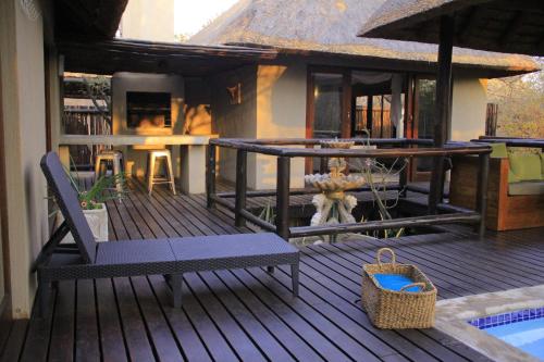 a deck with a bench and a table and chairs at Hoedspruit Raptors Lodge N16 in Hoedspruit