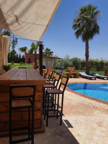 a patio with a table and chairs next to a pool at Villa Diaf Johanne in Aït Ourir