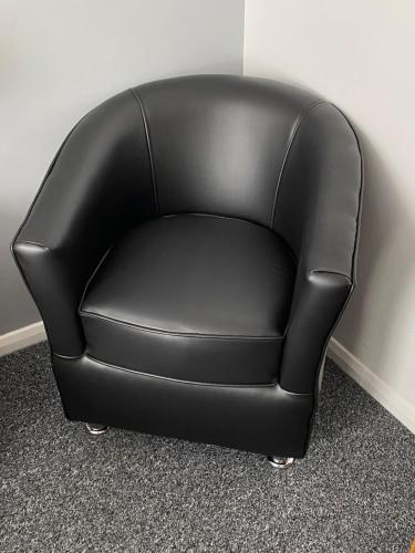 a black leather chair sitting against a wall at Apollo Guest House in Hastings