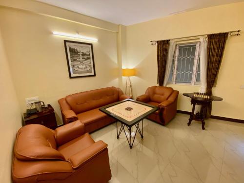 a living room with leather furniture and a table at Aakash Rooms and Cottages, in Ooty