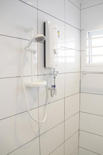a shower in a bathroom with white tiles at My Sweet Home in Malacca
