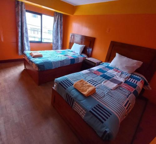 two beds in a room with orange walls at Big Mountain Hostel in Huaraz