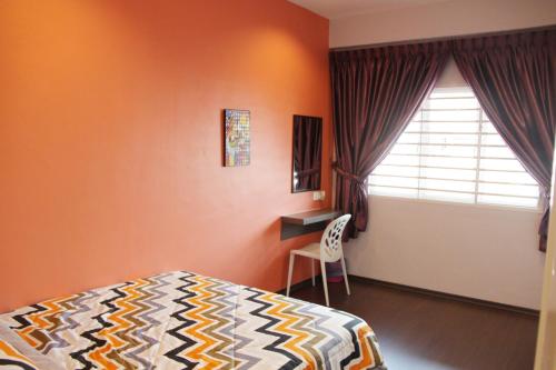 a bedroom with orange walls and a bed and a window at My Sweet Home in Malacca