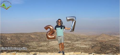 a man standing on a mountain holding two large pipes at Ein lahda camp-site in Dana