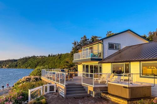 a large yellow house with a deck next to the water at Spyglass Beach House in Freeland