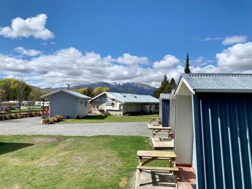 a picnic table and benches in a yard with buildings at Omarama TOP10 Holiday Park in Omarama