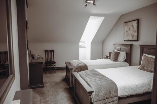 a hotel room with two beds and a window at Muskerry Arms Bar and B&B in Blarney