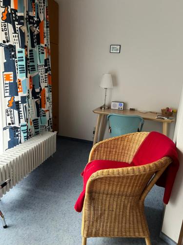 Zimmer mit einem Schreibtisch und einem Stuhl mit einer roten Decke in der Unterkunft Pension Thilo in Bad Wildbad