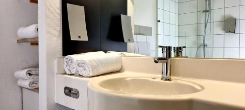 eXo Square Heidelberg/Schwetzingen - by SuperFly Hotels في شفيتزينجين: حمام مع حوض ومرآة ومناشف