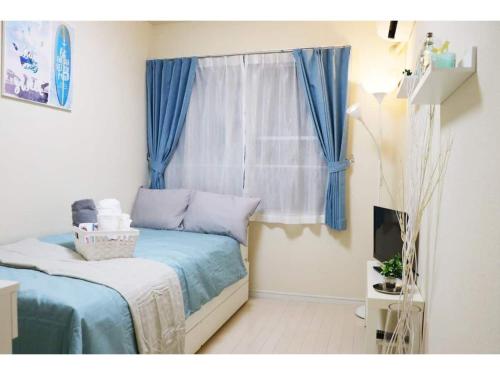 a bedroom with a bed and a window with blue curtains at OHANA TOKYO HOUSE - Vacation STAY 73207v in Tokyo