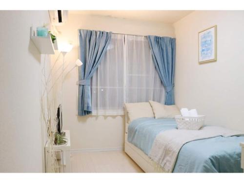 a bedroom with a bed and a window with blue curtains at OHANA TOKYO HOUSE - Vacation STAY 73223v in Tokyo