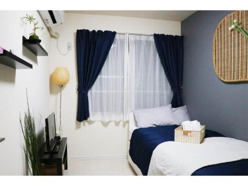 a bedroom with a bed and a window with blue curtains at OHANA TOKYO HOUSE - Vacation STAY 73655v in Tokyo