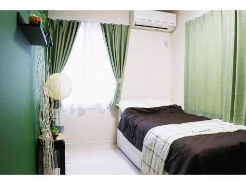 a bedroom with a bed and a window with green curtains at OHANA TOKYO HOUSE - Vacation STAY 71660v in Tokyo