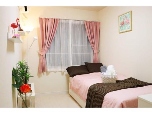 a bedroom with two beds and a window with pink curtains at OHANA TOKYO HOUSE - Vacation STAY 71661v in Tokyo