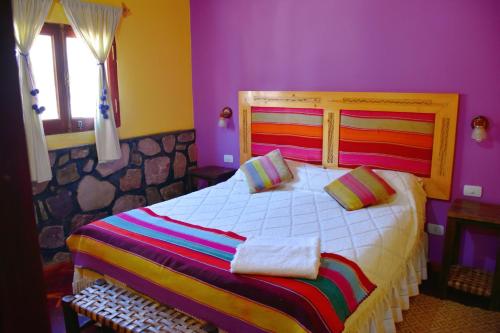 1 dormitorio con 1 cama grande y paredes moradas en Hostal Paseo de los Colorados en Purmamarca